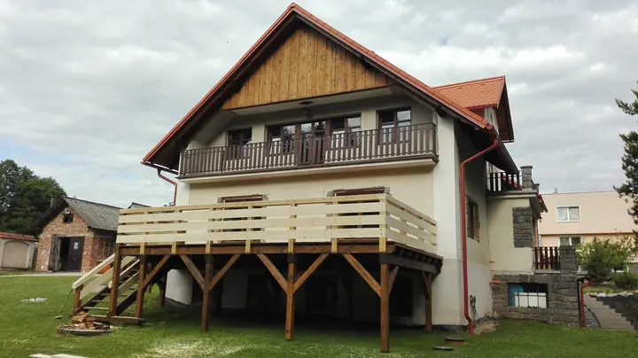 Dřevěný balkon nad terasou domu